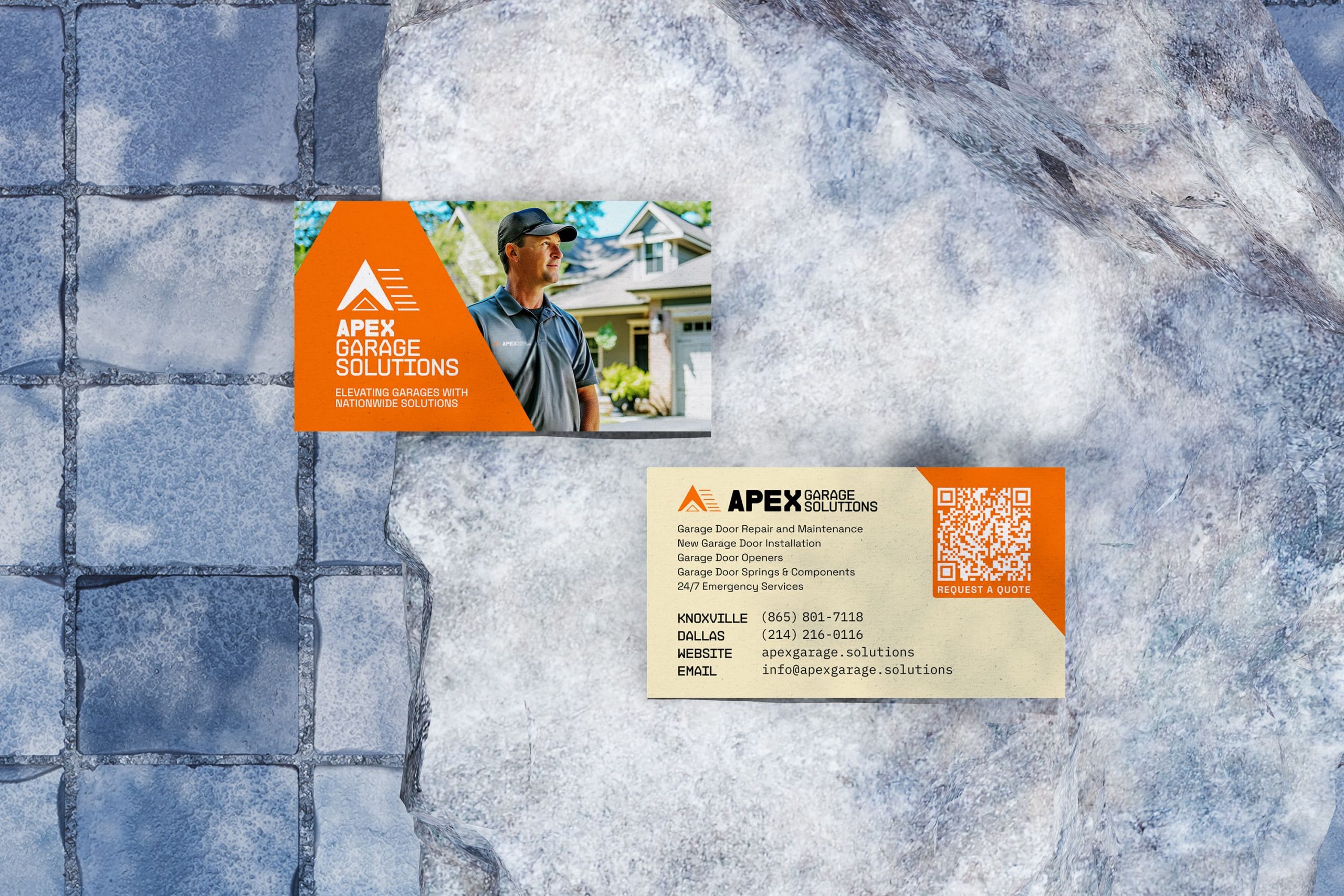 Top-down flat lay of the APEX Garage Solutions front and back business cards arranged on grey stone slabs against a blue textured background.